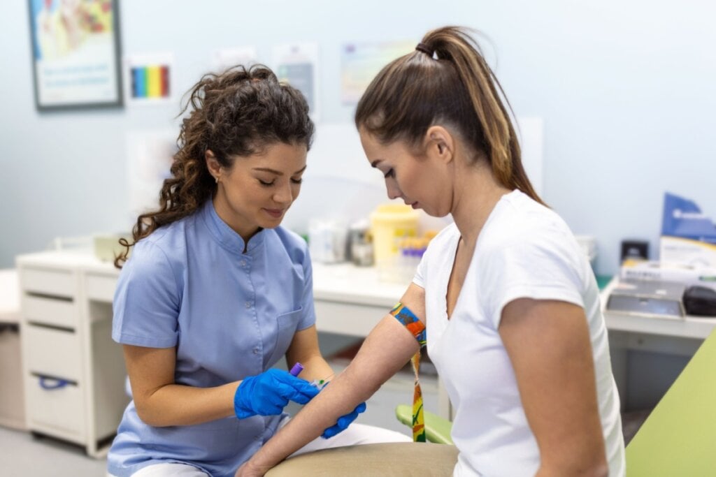 Enfermeira sentada preparando para tirar sangue de paciente