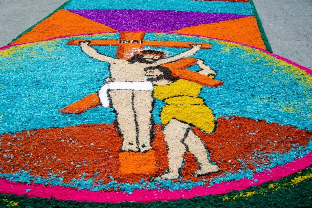 Tapete de rua colorido com figura de Jesus sendo crucificado