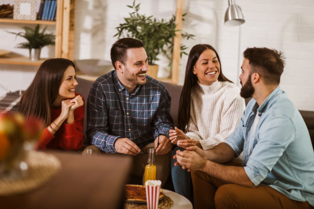 grupo de amigos sentados em ambiente interno rindo e conversando