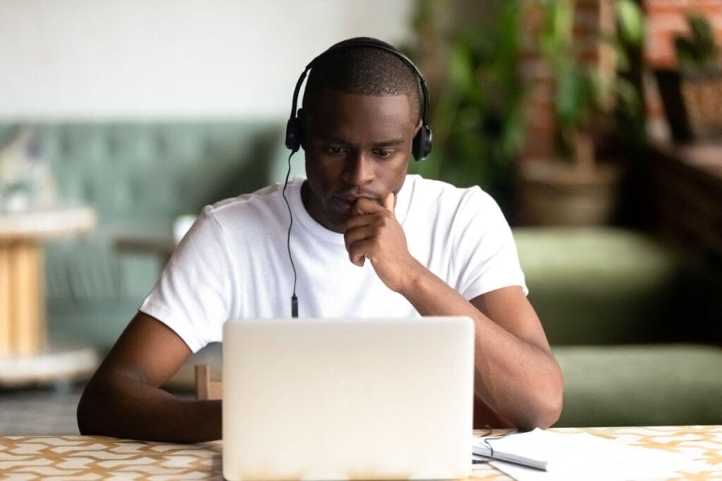 Jovem estudando concentrado no notebook e usando fones de ouvido