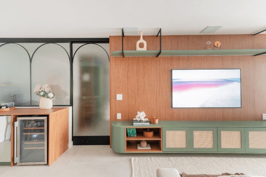 Sala decorada com móveis em madeira e o móvel abaixo da TV é verde com palhinha