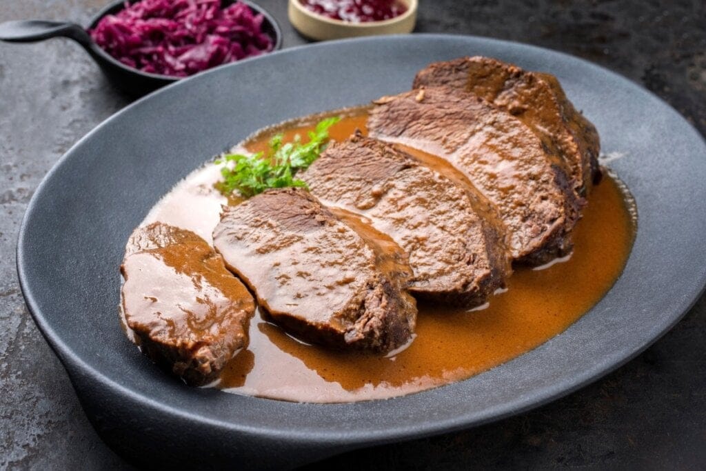 Carne assada ao molho marrom alemão em prato cinza