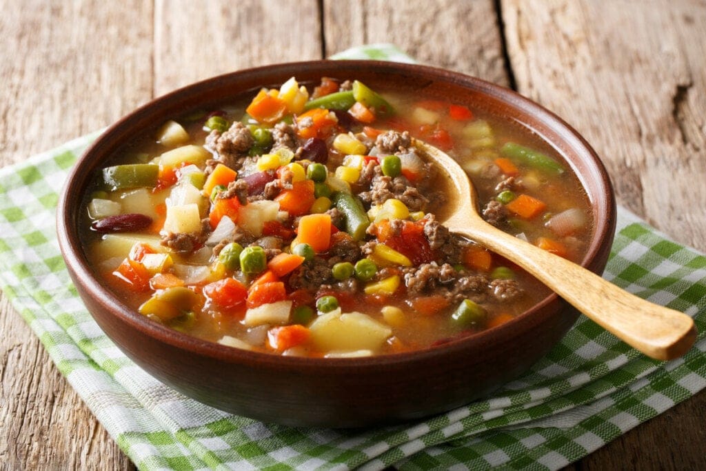 Recipiente marrom com sopa de legumes e carne moída