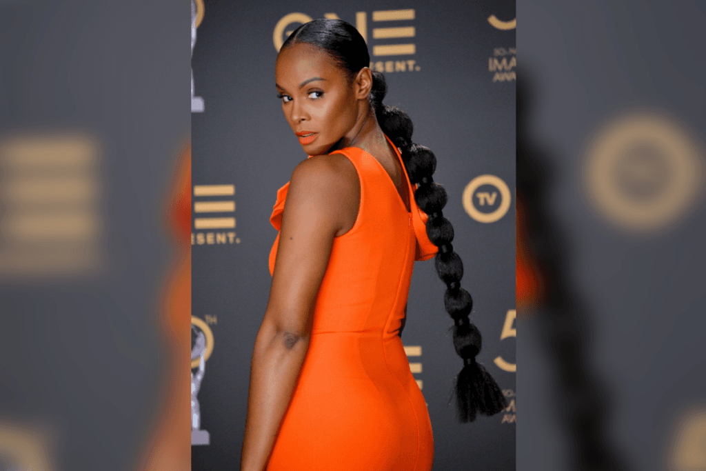Mulher de costas com rabo de cavalo estilo bubble, usando vestido laranja em um evento