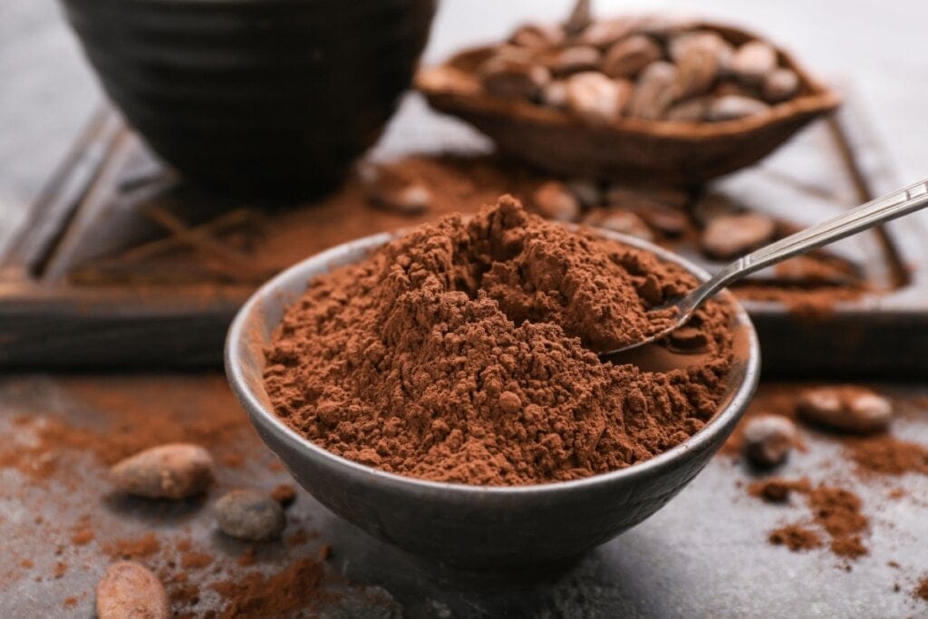 Pote de cerâmica com chocolate em pó em cima de mesa de madeira