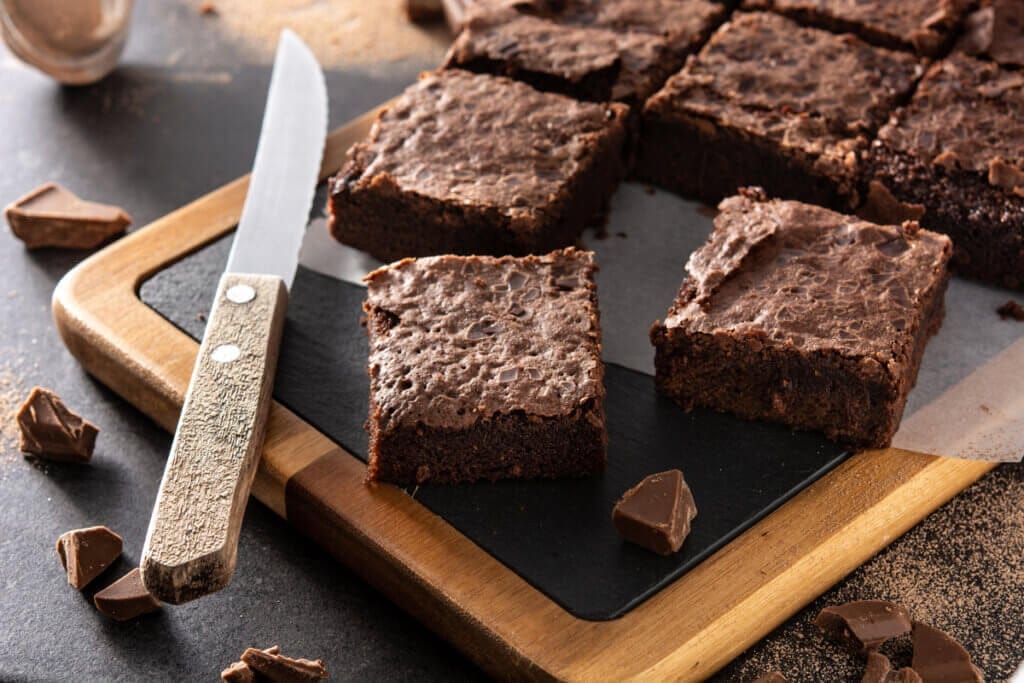 Pedaços de brownie de chocolate em cima de uma tábua e uma faca ao lado