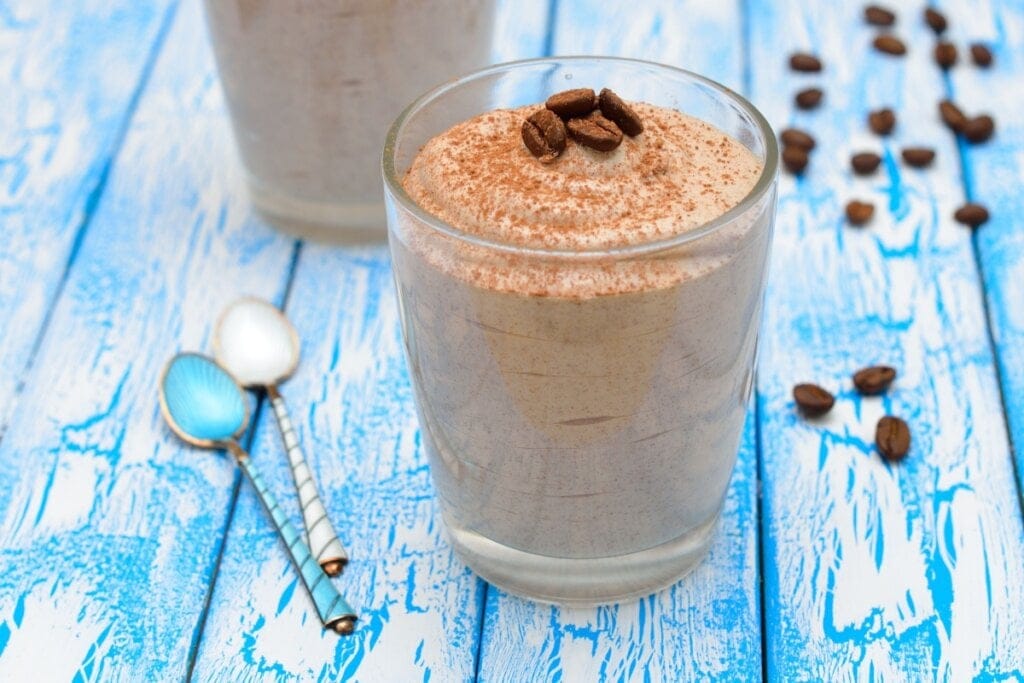 Copo de vidro com mousse de café decorado com chocolate em pó e grãos de café