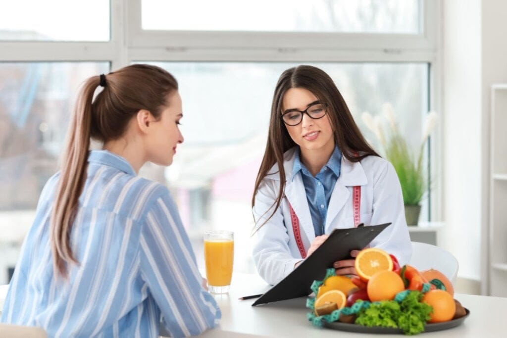nutricionista e pacientes sentadas uma de frente para a outra. nutricionista mostra prancheta para paciente