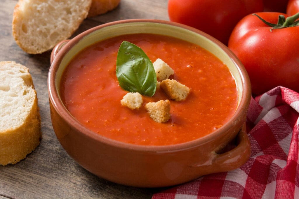 Panela de vidro com sopa de tomate e pedaços de pão