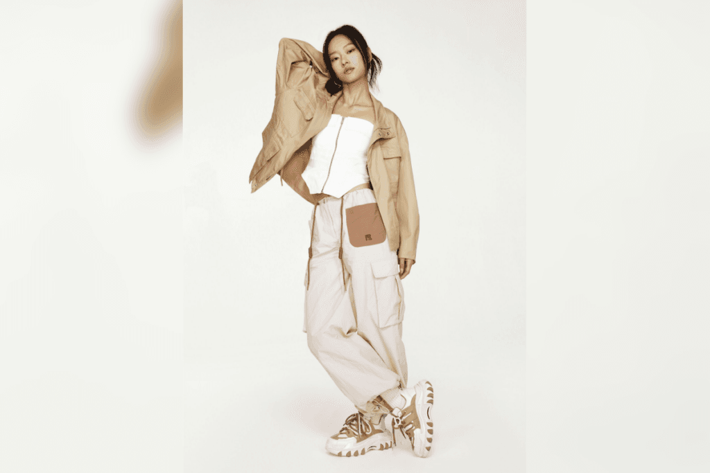 Mulher posando com jaqueta clara, calça cargo larga e tênis chunky em estúdio de fundo branco