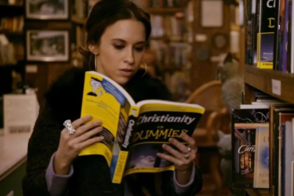 Cena do filme "Match Divino" com uma mulher sentada lendo um livro com capa amarela