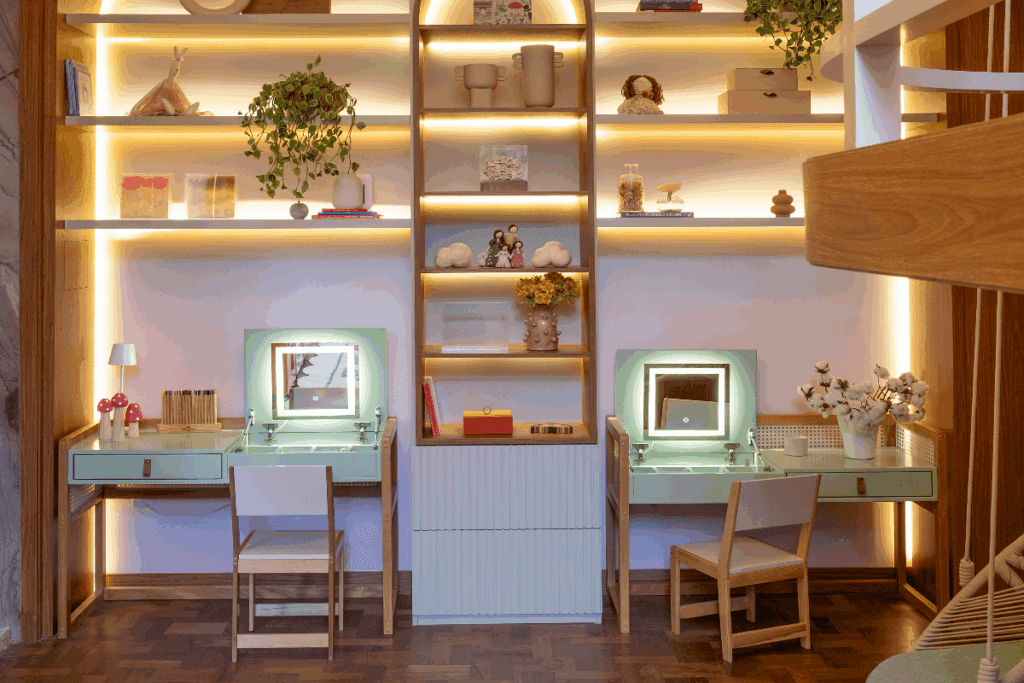 Prateleiras na parede com iluminação de led, e duas penteadeiras e escrivaninhas na cor verde com duas cadeiras de madeira 