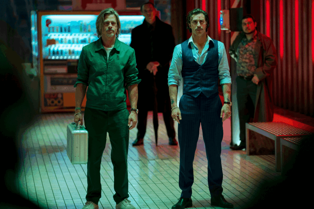 Dois homens em um ambiente com reflexo de luz verde, um deles está vestido de verde e tem uma maleta na mão e outro está usando roupas sociais azul escuto e camisa de botão branca
