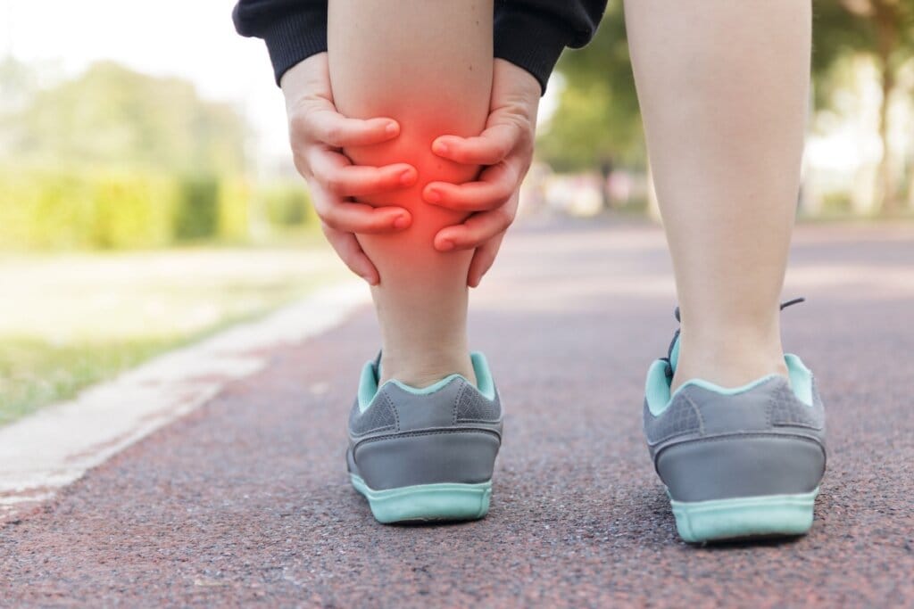 Imagem de uma pessoa com as duas mãos na panturrilha e a ilustração de uma mancha vermelha em cima  