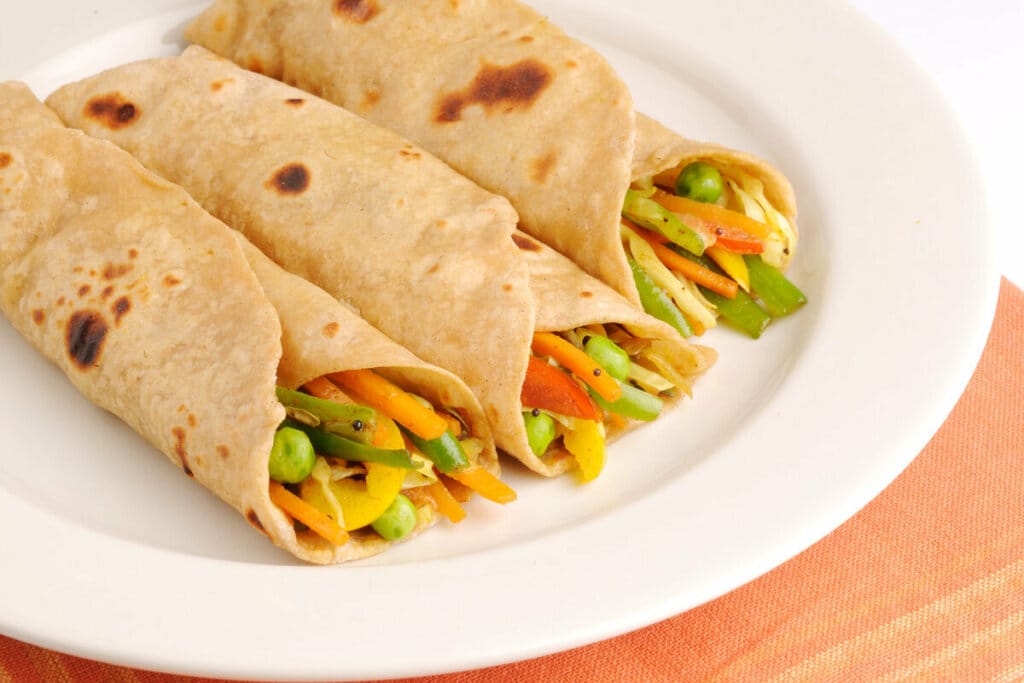 Três panquecas recheadas com legumes em um prato branco