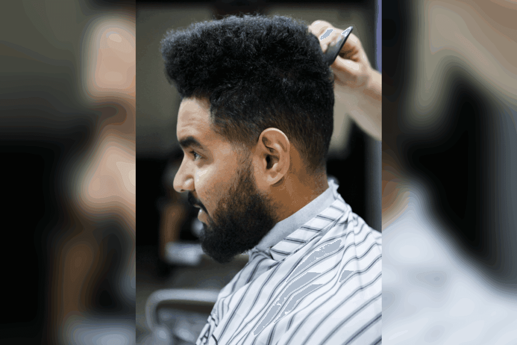 Homem com cabelo volumoso no topo e laterais raspadas, recebendo acabamento no corte Flat Top em barbearia