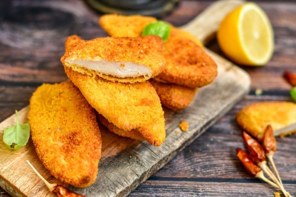 cinco filés de frango à milanesa dourados e crocantes em cima de tábua