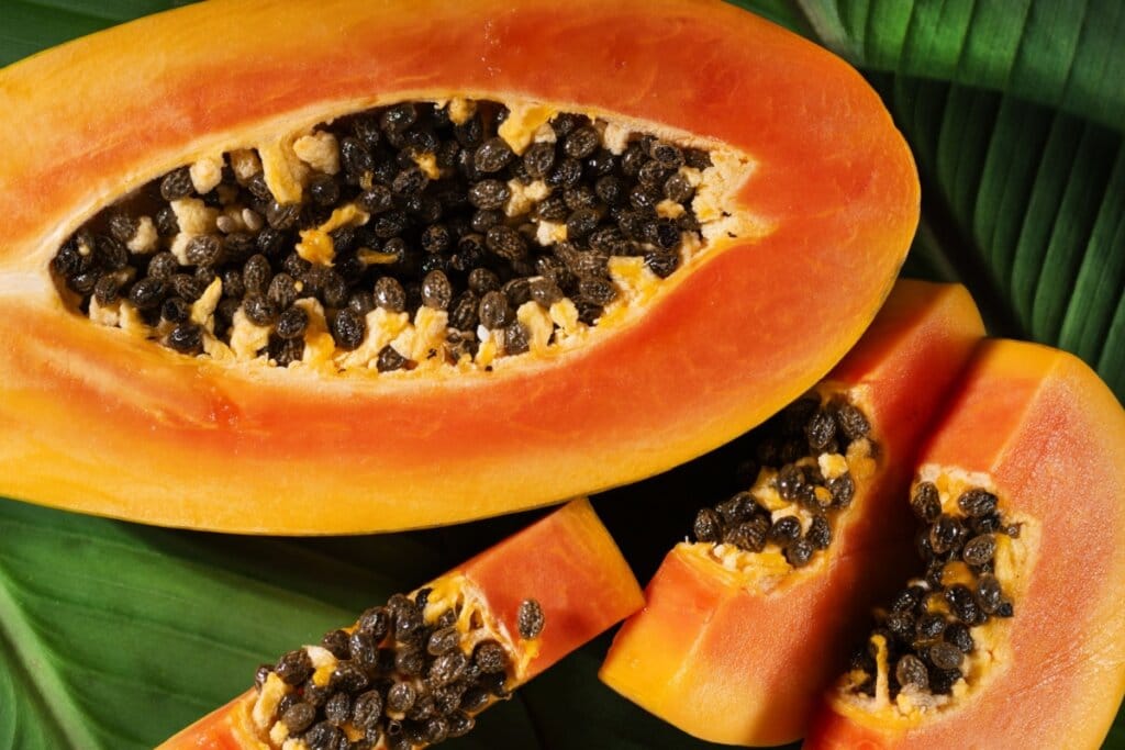 imagem de mamão aberto e fatias da fruta com sementes