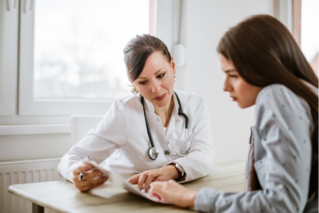 Mulher e médica sentadas olhando para um papel