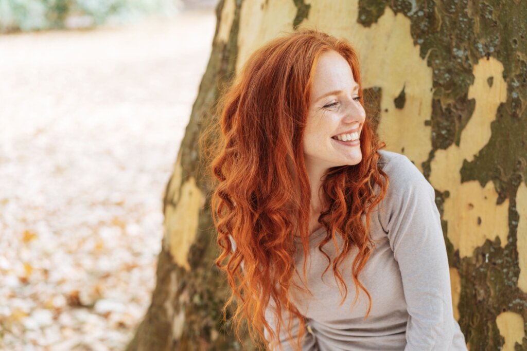Mulher com cabelo liso ruivo ferrugem ao ar livre e olhando para o lado
