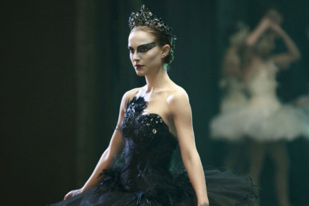 Natalie Portman vestindo um vestido preto, com maquiagem nos olhos combinando, e usando uma coroa 