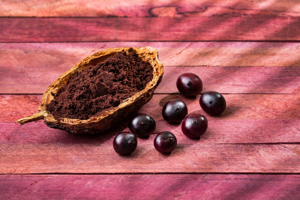 Açaí ao lado de seu pó sobre uma superfície de madeira rosa