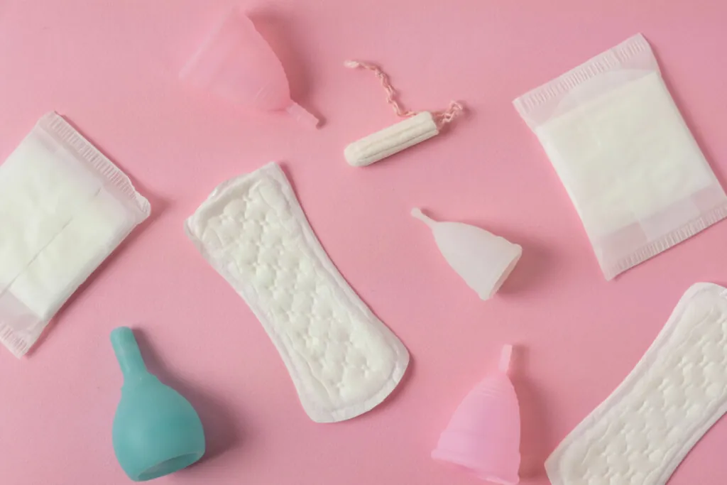 Absorventes e coletores menstruais em fundo rosa