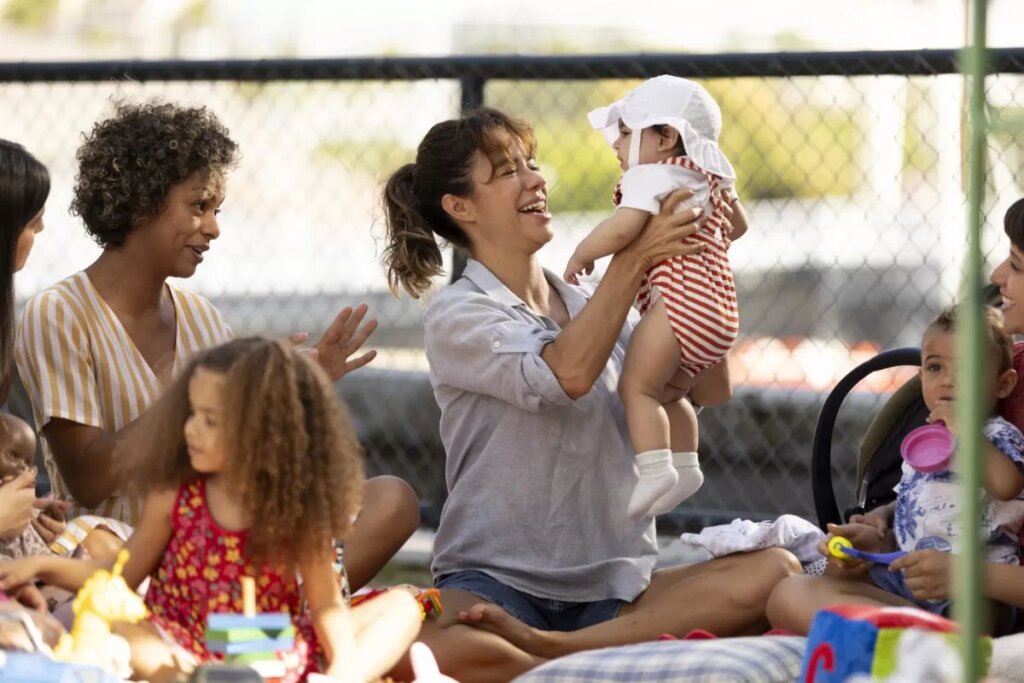 Atriz Miá Mello em um parque e segurando um bebê em cena de "Mãe Fora da Caixa"