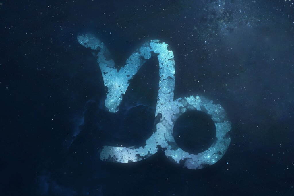 símbolo do signo de capricórnio em um fundo azul marmorizado sobre fundo azul-escuro estrelado