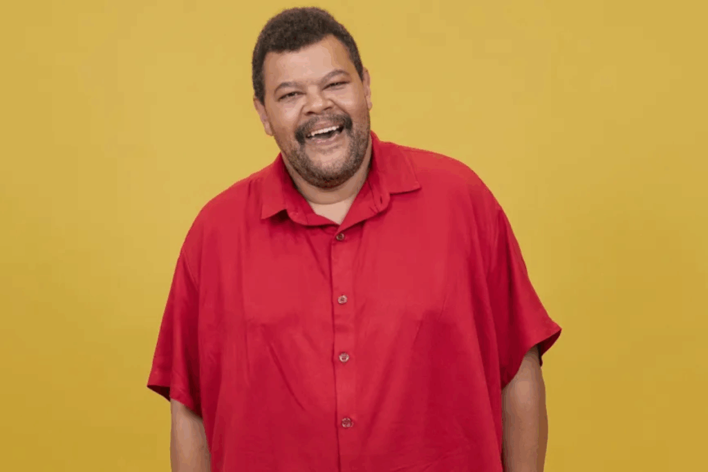 Babu Santana de camisa vermelha sob um fundo amarelo