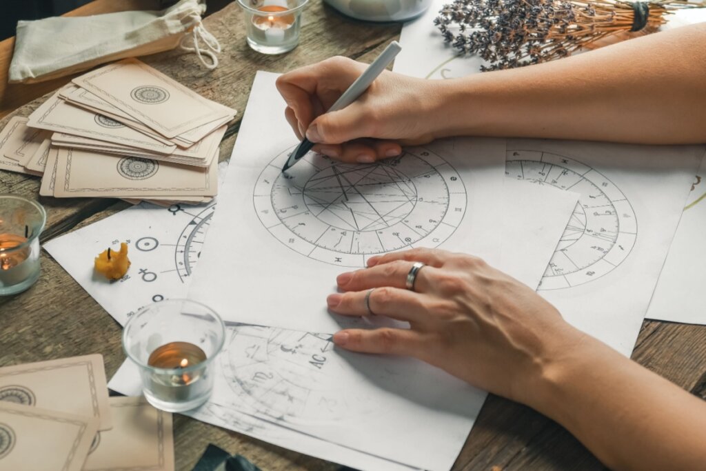 Mãos calculando Mapa Astral em uma folha branca