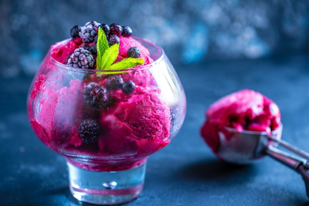 taça de vidro com bolas de sorvete vermelho e frutas vemelhas