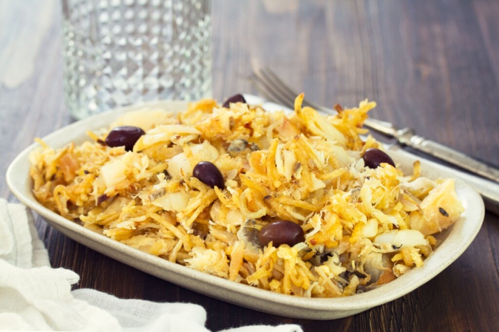 Bacalhau à Brás servido em tigela branca de cerâmica em cima de mesa de madeira