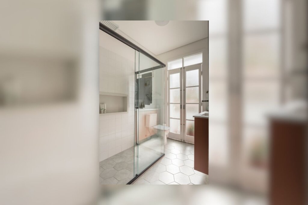 Box em L em um banheiro com paredes brancas e janela do teto ao chão 