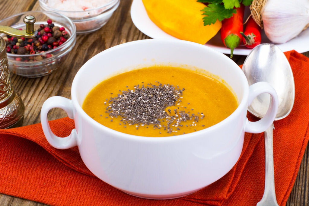 Creme de abóbora dentro de uma panela branca com sementes de chia