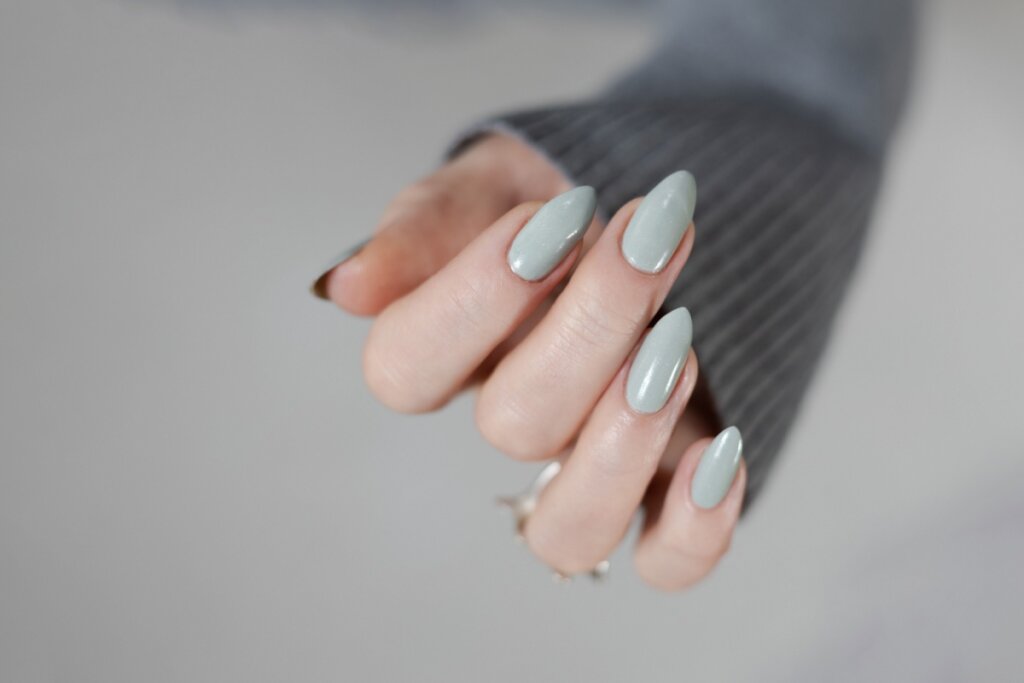 Mãos com unhas longas pintadas com esmalte cinza-claro