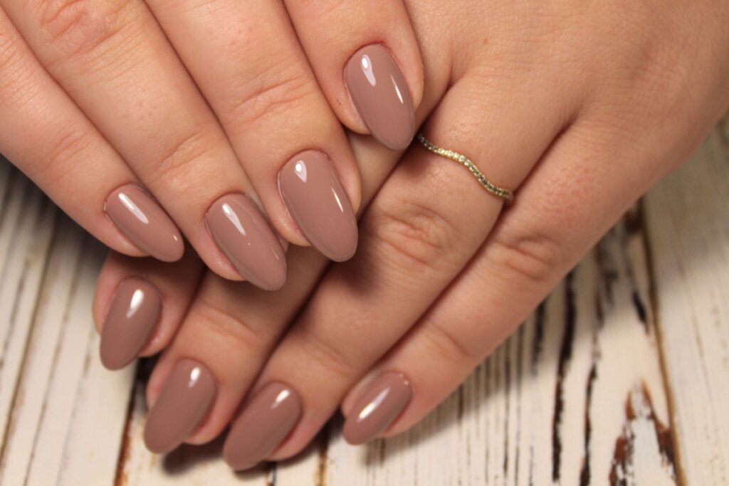 Mãos com unhas longas pintadas com esmalte marrom claro