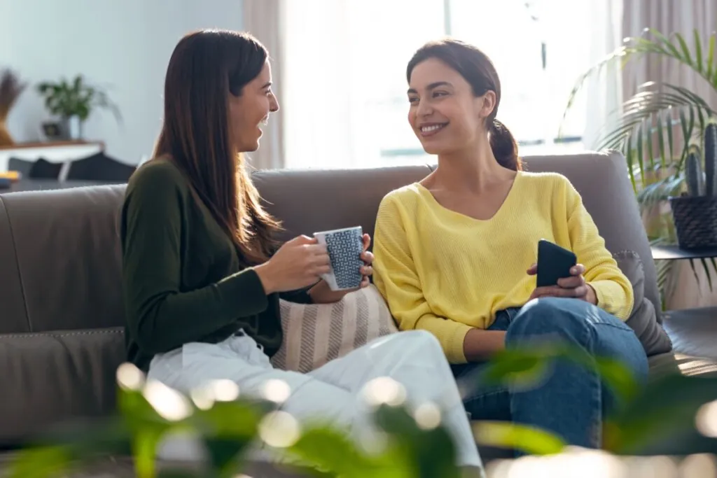 Amigas sentadas no sofá conversando e tomando café