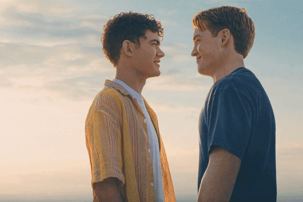 Dois jovens se encarando e sorrindo ao ar livre, com céu claro ao fundo