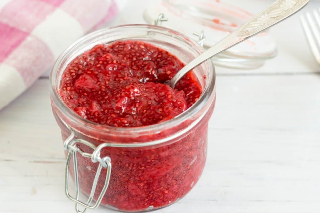 Recipiente de vidro com geleia vermelha e sementes de chia