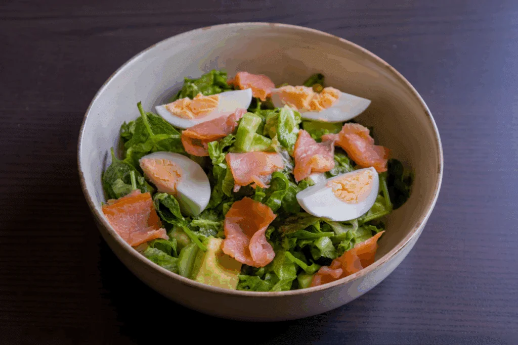 Recipiente branco com salada com salmão, ovo e abacate