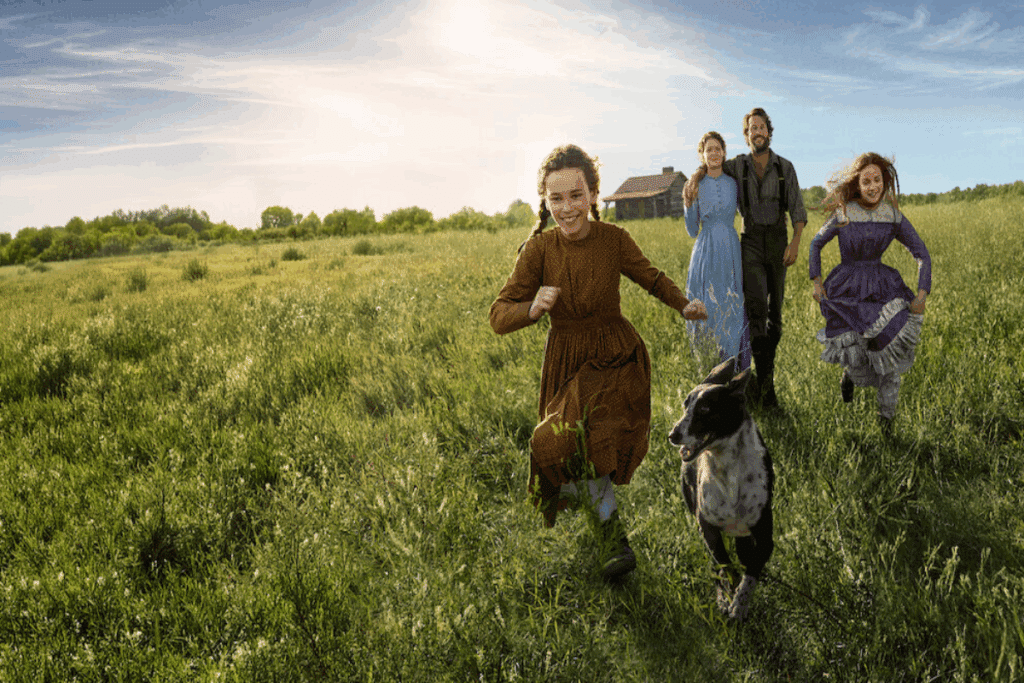 Imagem de um casal com a duas filhas e um cachorro correndo no meio de campo com sol ao fundo 