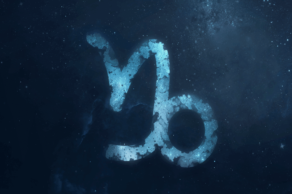 A imagem mostra o símbolo do signo de capricórnio em destaque sobre um fundo que representa o espaço, repleto de estrelas e nebulosas. O ícone aparece em tons de azul, com textura que se mistura ao cenário cósmico.