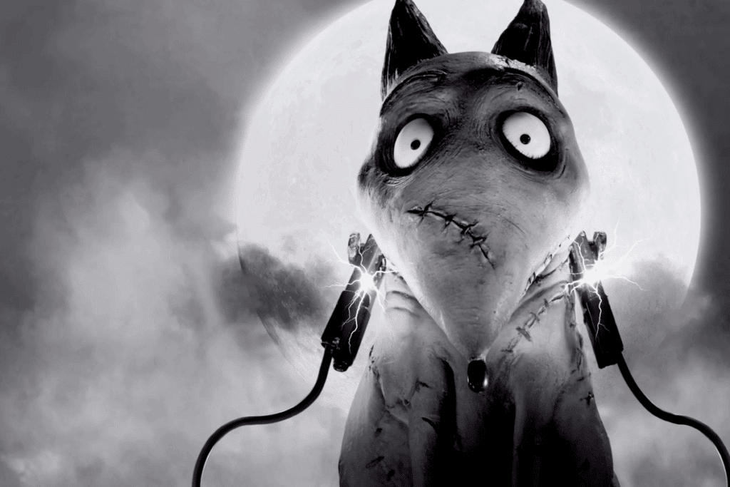 Imagem em preto e branco do filme Frankenweenie: o cachorro Sparky, com o corpo remendado por costuras, olhos grandes e arregalados e orelhas pontudas, aparece de frente, com dois parafusos no pescoço soltando faíscas elétricas e ligados a cabos, diante de uma grande lua cheia em um céu nublado.